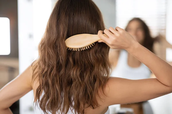 Lady Brossage de cheveux avec brosse à cheveux en bois dans la salle de bain, vue arrière — Photo