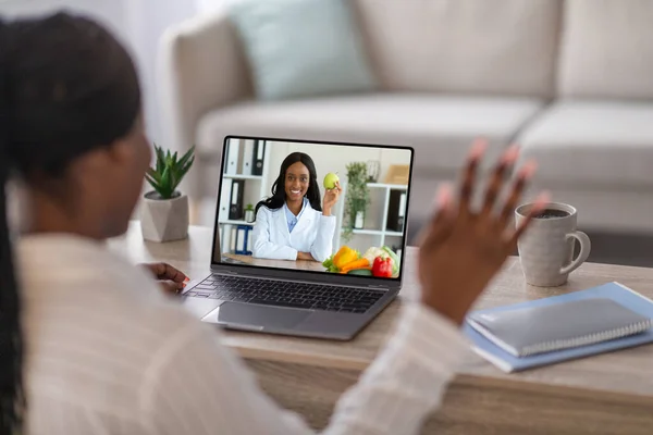 African american woman having video chat with dietitian, home interior — Stock Photo, Image