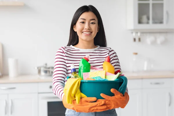 Felice donna asiatica con strumenti di pulizia in piedi in cucina — Foto Stock