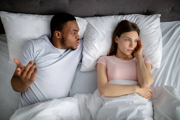 Millennial interracial couple quarrelling in bed, feeling angry, facing family problems, top view — 스톡 사진