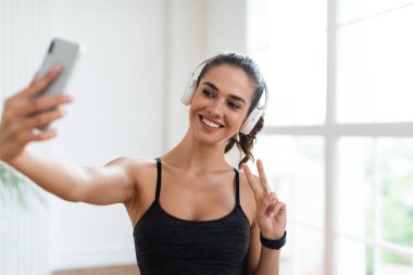 Spor arası sırasında spor salonundaki kadın akıllı telefondan selfie çekiyor.