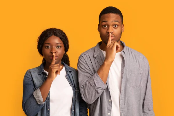 Não digas uma palavra. Homem preto e mulher mantendo os dedos nos lábios — Fotografia de Stock