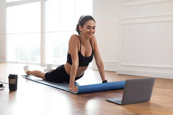 Jonge vrouw stretching terug op mat met pc — Stockfoto