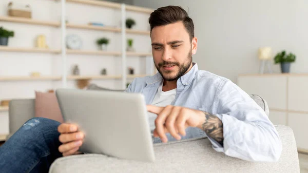 Nahaufnahme eines gutaussehenden Mannes, der sich auf einem Sofa zurücklehnt, zu Hause ein modernes Polster benutzt und sich auf der Couch im Wohnzimmer ausruht — Stockfoto