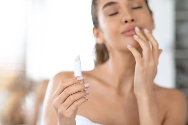 Mujer atractiva aplicando lápiz labial tocando los labios hidratando la piel en el baño — Foto de Stock