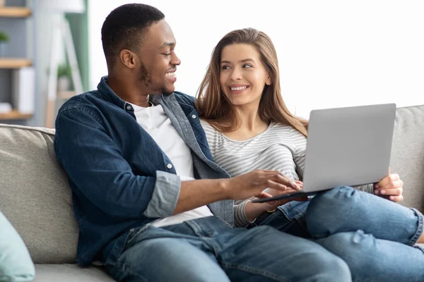 Buchen Sie Urlaub. Glückliches multikulturelles Paar nutzt Laptop zu Hause gemeinsam — Stockfoto