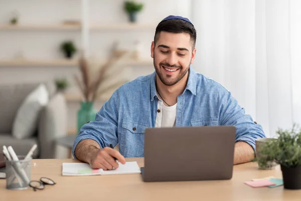 Lächelnder israelischer Mann arbeitet zu Hause am Laptop — Stockfoto