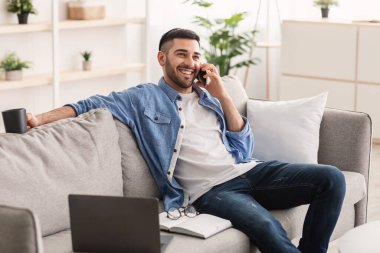Gülümseyen Yahudi adam evde çalışıyor ve telefonla konuşuyor.
