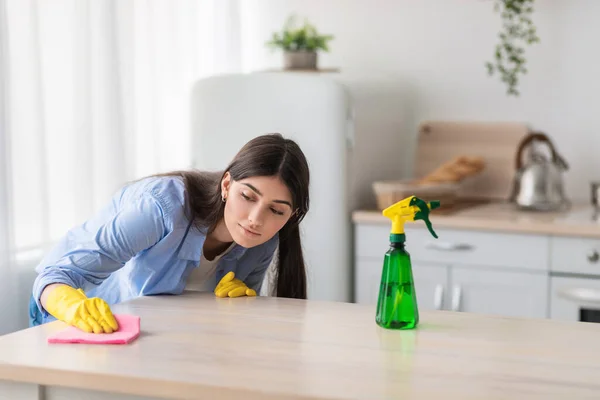 Primo piano di focalizzata giovane donna tavola di pulizia con panno — Foto Stock