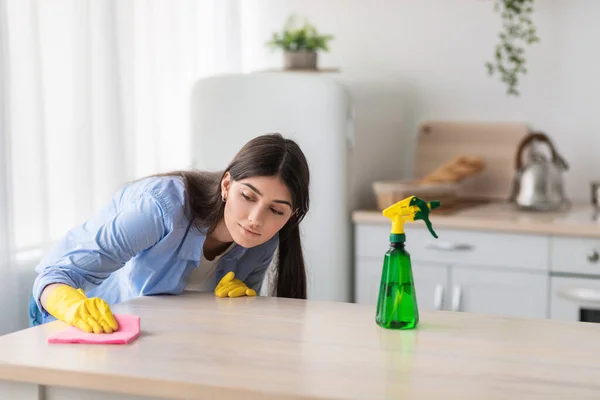 Close-up van gerichte jonge vrouw schoonmaak tafel met doek — Stockfoto