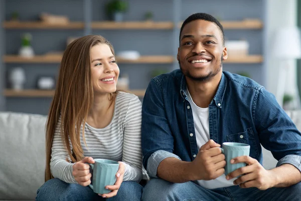 Yurtiçi Hobi. Mutlu ırklar arası eşler oturma odasında dinlenirken kahve içiyorlar. — Stok fotoğraf