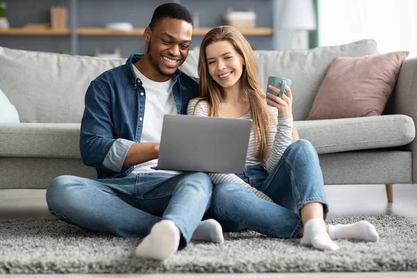 Innenpolitische Weichenstellungen. Joyful jung exotisch ehepaare rest mit laptop bei zuhause — Stockfoto