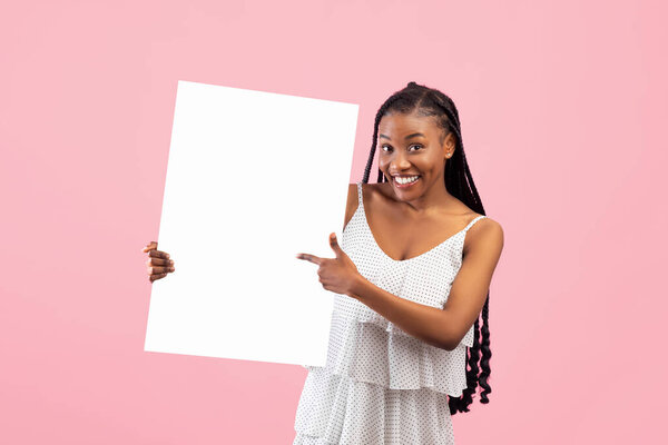Smiling African American woman pointing at empty banner with space for your design on pink background