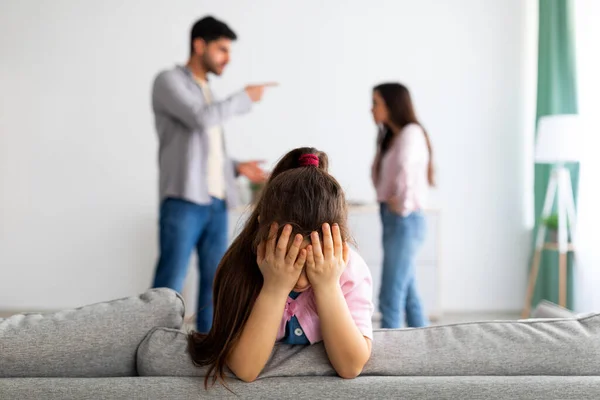 Family crisis. Little girl crying, closing face with hands while her angry parents fighting on the background — 图库照片