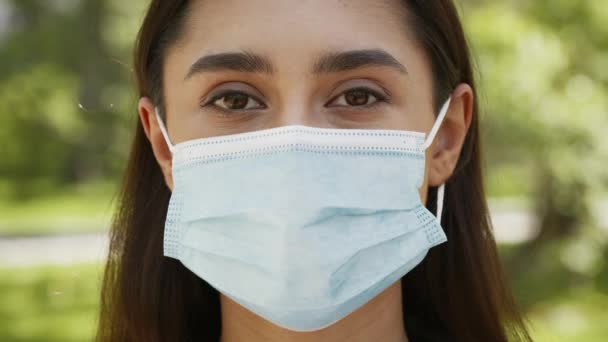 Jonge vrouw draagt beschermende gezichtsmasker poseren buiten — Stockvideo