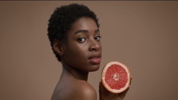 Atractiv negru doamnă Posing cămașă Holding grapefruit peste fundal bej — Videoclip de stoc