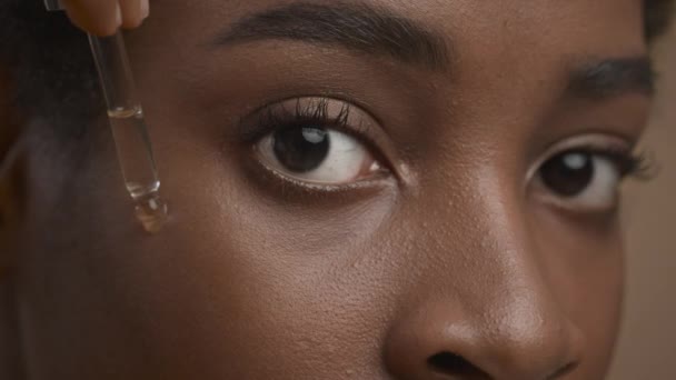 Donna nera che applica siero facciale con contagocce, sfondo beige, primo piano — Video Stock
