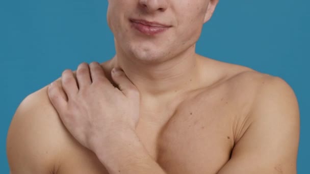 Trauma olahraga. Pria tak dikenal menggosok bahu telanjangnya yang menyakitkan, menderita sakit otot, latar belakang studio biru — Stok Video