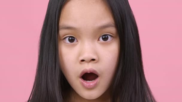 Sincere shock feeling. Amazed little girl looking at camera with open mouth, feeling shocked and amazed, pink background — Stock Video