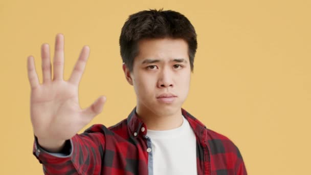 Asiático chico gestos parada a cámara sacudiendo cabeza, naranja fondo — Vídeos de Stock
