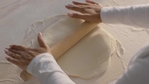 Homemade bakery. Black woman baker rolling out raw dough with wooden pin, preparing pastry, pizza or pasta at kitchen — Wideo stockowe