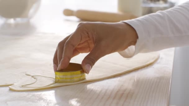 การผลิตขนมอบ ผู้หญิงผิวดําที่จําไม่ได้ ตัดคุ้กกี้บนโต๊ะในครัว ใช้เครื่องตัดโลหะบนแป้งดิบ — วีดีโอสต็อก