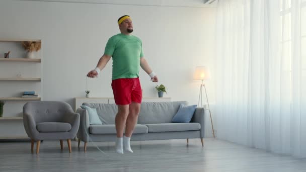Pria gemuk melompat-lompat dengan tali tanpa sepatu olahraga, melukai kakinya dan menderita rasa sakit, bekerja di rumah — Stok Video