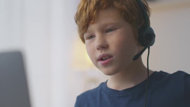 Les enfants et le cyber sport. Petit garçon portant un casque avec micro, parlant à des amis en ligne, jouant sur un ordinateur portable — Video