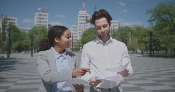 Afrikaans-Amerikaanse vrouw en blanke man collega 's bespreken zakelijke documenten, geven high five aan elkaar — Stockvideo