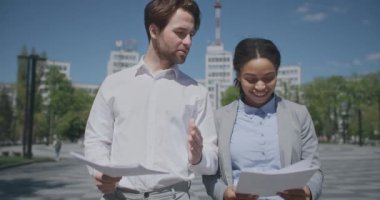 Başarılı bir ortaklık. Genç, neşeli, çeşitli iş adamları proje belgelerini tartışıyor, dışarıda yürümekten keyif alıyorlar.