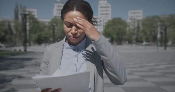 Problemas de negocios. Joven mujer afroamericana desesperada gerente de la lectura de documentos, pensando en formas de solución — Vídeo de stock