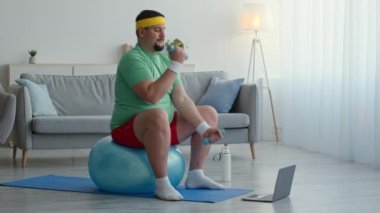 Kilolu adam spor kıyafetleri içinde, halterlerle egzersiz yapıyor, formda top oynuyor ve dizüstü bilgisayarda video dersi izliyor.