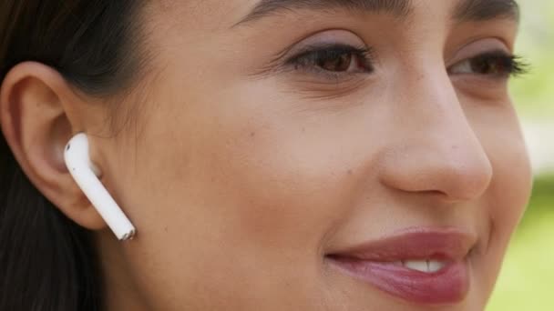 Woman Wearing Earbuds Listening To Music Looking Aside Outdoors, Closeup — Stockvideo