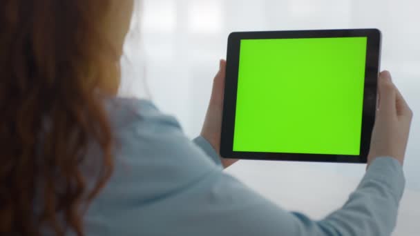Nahaufnahme eines unkenntlichen Mädchens, das online Videos auf einem digitalen Tablet mit grünem Chroma-Schlüsselbildschirm anschaut, leerer Raum — Stockvideo