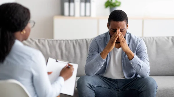 Homem negro desesperado sofrendo de colapso nevrálgico ou depressão, tendo sessão no escritório de psicólogos, panorama — Fotografia de Stock