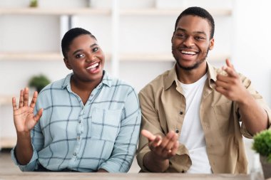 Mutlu Afrikalı çift el sallıyor, içerde oturan kameraya gülümsüyor.