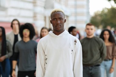 Çok ırklı bir grubun başında duran ciddi bir Afrikalı Amerikalı.