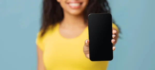 Makieta do aplikacji lub strony internetowej. Afroamerykanka pokazuje pusty ekran telefonu komórkowego na niebieskim tle — Zdjęcie stockowe