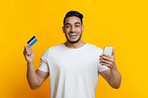 Happy arab guy with smartphone and credit card — Zdjęcie stockowe