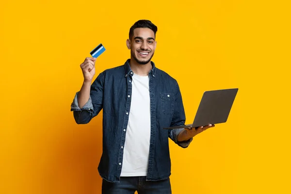 Happy arab guy with laptop and credit card — Zdjęcie stockowe