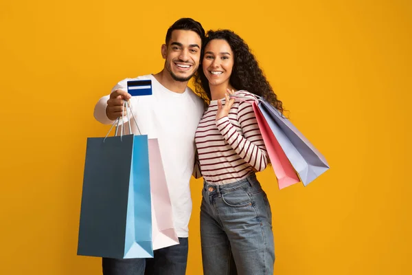 Kredi kartı ve alışveriş torbalarıyla Orta Doğulu mutlu bir çiftin portresi. — Stok fotoğraf