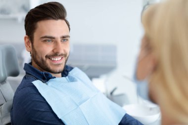 Rahatlamış yakışıklı adam dişçisine gülümsüyor.