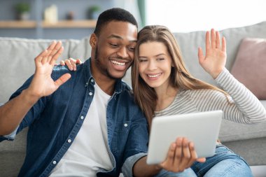 Web sohbeti. Irklar arası çift dijital tablet tutuyor ve Webcamera 'ya el sallıyor.