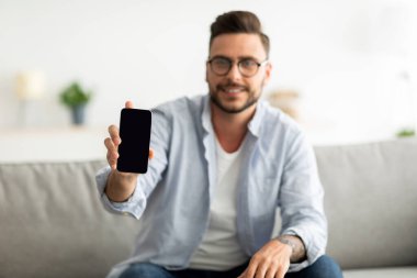 Bu web sitesini tavsiye ederim. Genç adam kameraya boş ekranlı akıllı telefonu gösteriyor, reklamınız ya da tasarımınız için model alın.