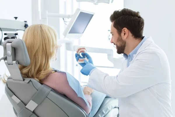 Beraded doctor dentist showing jow miniature to patient — Stock Photo, Image