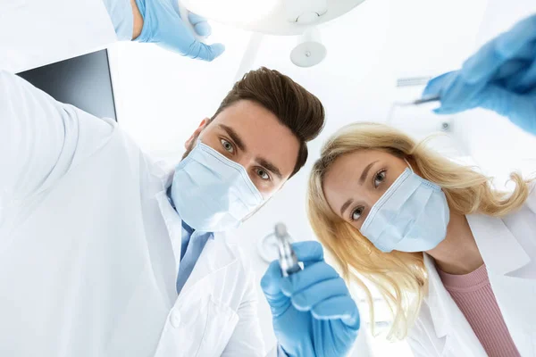 마스크를 쓴 두 명의 치과 의사 와고 무장갑을 사용하여 치료하고 있다 — 스톡 사진