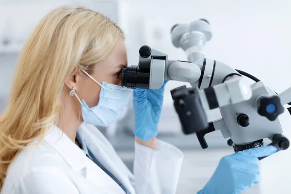 Dentista feminina usando equipamentos modernos para tratar na clínica odontológica — Fotografia de Stock