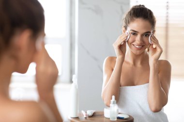 Banyoda pamuk pedlerle poz veren genç bayan.