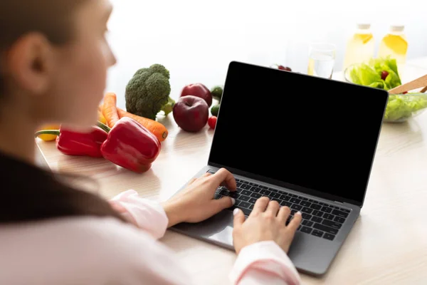 Žena pomocí notebooku s prázdnou obrazovkou sedí za stolem — Stock fotografie