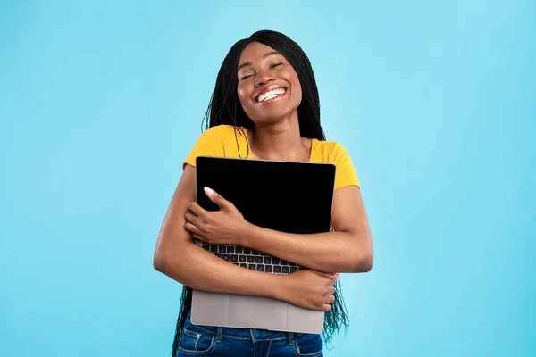 Szczęśliwy Afryki amerykanka gospodarstwa przytulanie laptop komputer, niebieskie tło — Zdjęcie stockowe